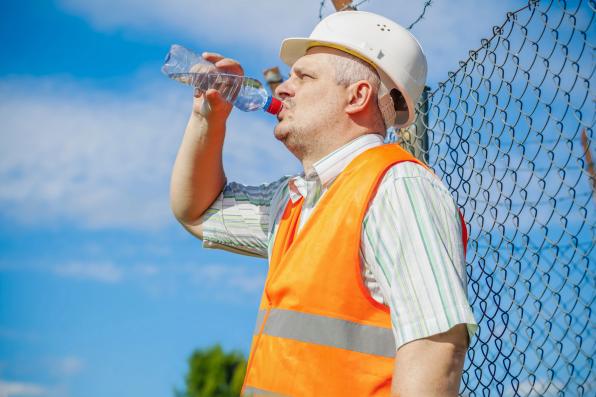 nell'immagine c'è un lavoratore sotto il sole che beve dell'acqua